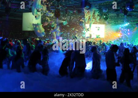 Many people dance and have fun at Big Foam Party in night club. Stock Photo