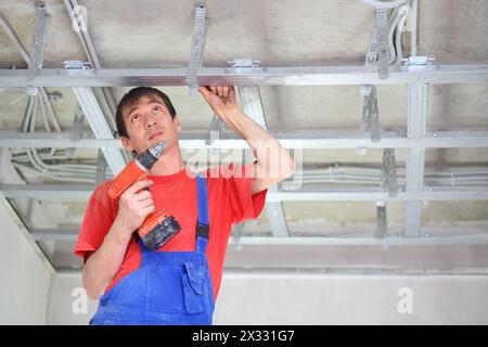 Builder fastens profile using cordless screwdriver Stock Photo