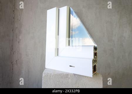 Sample PVC window stands on a concrete block, in the glass reflects the blue sky with clouds Stock Photo