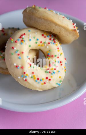 Small homemade donuts covered in white chocolate and colorful toppings Stock Photo