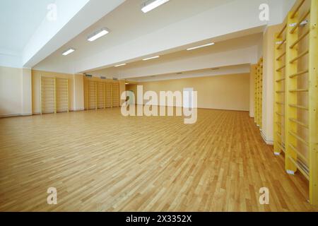 Empty school gymnasium with yellow floor and climbing near walls. Stock Photo