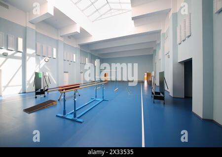 Empty school gymnasium with blue floor and gymnastic apparatus. Stock Photo