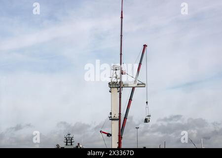 Men at work demolishing a large crane at Devonport Dockyard beside the River Tamar. Some on the crane itself and others in a cage suspended from anoth Stock Photo