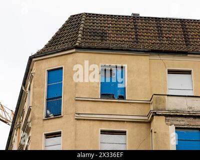 Old building exterior with cracks in the wall and broken windows. Abandoned house facade in a residential district. The poor owner doesn't renovate. Stock Photo