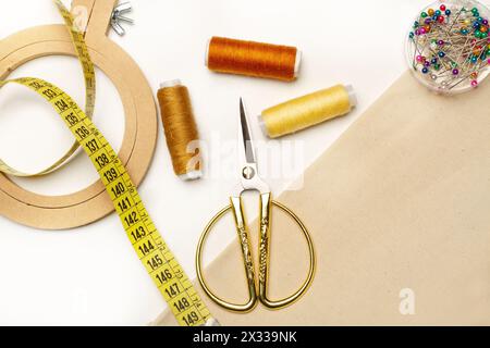 Colored thread spools, scissors and a embroidery hook on a white and brown background with coppy space Stock Photo
