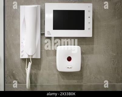 White plastic video intercom is hanging on the wall. Stock Photo