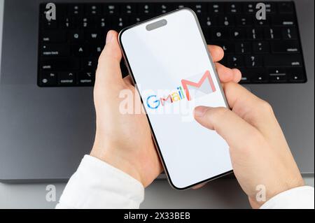 New York, USA - April 6, 2024: Popular Gmail mobile app on smartphone screen in hands on laptop keyboard background Stock Photo