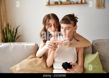 Two women in comfy attire sitting on a couch, engrossed in ring. Stock Photo