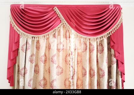 Luxury curtains with a red lambrequins on the window in a modern room Stock Photo