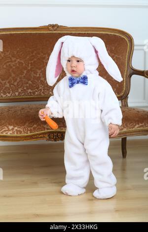 Little boy in costume bunny holding carrot Stock Photo