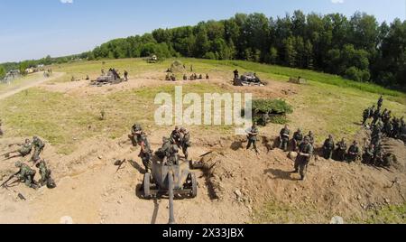 RUSSIA, MOSCOW - JUL 12, 2014: Soldiers in uniform of World War II stand near guns on battle field at spring sunny day. Aerial view. Photo with noise Stock Photo