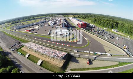 RUSSIA, MOSCOW - JUL 12, 2014: Sports cars passes by tribunes with people at summer sunny day. Aerial view (Photo with noise from action camera) Stock Photo