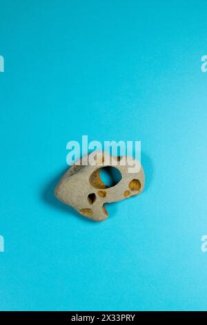 A hag stone against a blue background. Stock Photo