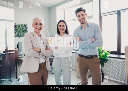 Photo of successful positive business people group stand in office with crossed arms Stock Photo