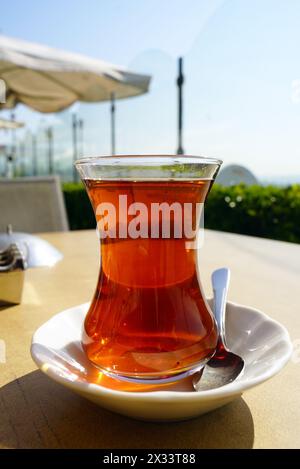 Black tea in a traditional Turkish glass, standing on the table of a street cafe in Istanbul Stock Photo