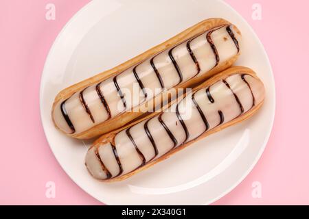 Delicious eclairs covered with glaze on pink background, top view Stock Photo