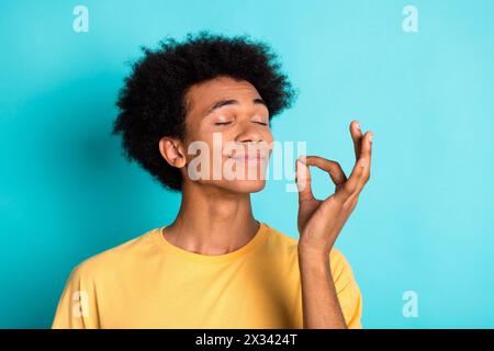 Photo of joyful guy with afro hairdo dressed yellow t-shirt eyes closed dream about tasty cake isolated on turquoise color background Stock Photo