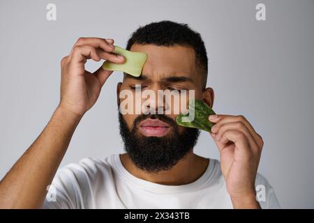 African american handsome man holds gua sha for skincare routine. Stock Photo