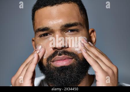 A bearded man gently shaves his face in his skin care routine. Stock Photo