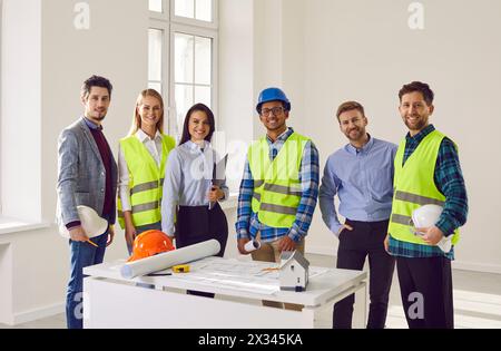 Team of construction workers and engineers in hardhats discussing projec Stock Photo