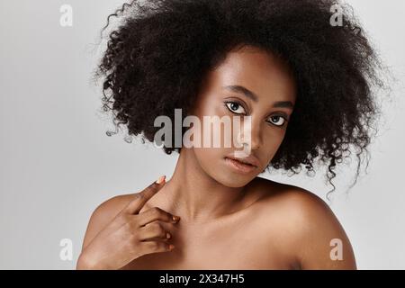 A stunning African American woman with curly hair in a studio, striking a pose for a portrait. Stock Photo