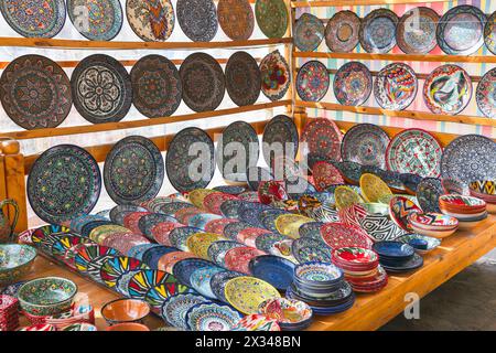 An assortment of handmade Uzbek plates and bowls with colorful traditional patterns are put up for sale at a street market in Bukhara Stock Photo