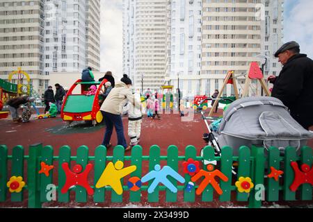 MOSCOW - FEB 13, 2016: People walk on children playground and listen bass band in Elk Island residential complex Stock Photo