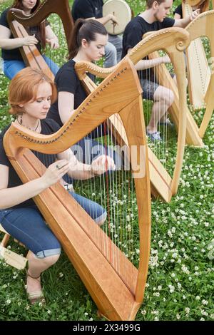 Six young musicians perform playing harps outdoors in park. Stock Photo