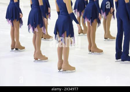 Skaters in beautiful costumes and skates on the ice in the sports complex, view below waist Stock Photo