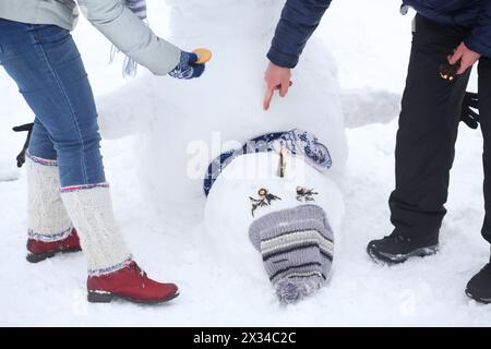 Hands of woman and man making inverted snowman at winter day Stock Photo