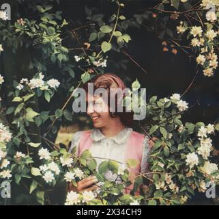 A young Princess Elizabeth surrounded by Philadelphus blossoms in the Royal Lodge, Windsor gardens, dated 1941. At just 15, living through World War II's hardships, her experiences would forge the resilience of a future Queen, marking a pivotal chapter in both her life and Britain's history. Stock Photo