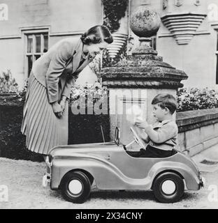 Queen Elizabeth II is shown with Prince Charles on his 4th birthday in this photograph taken at Balmoral in 1952. The young prince is pictured playing in his toy car and with a hand puppet, a scene that starkly contrasts his future responsibilities as the King of the UK and Commonwealth realms. Stock Photo