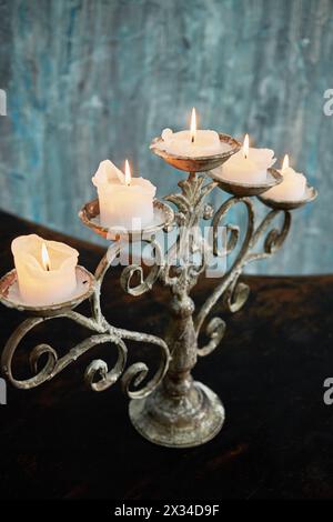 Old candlestick with five burning candles stands on surface of grand piano lid. Stock Photo