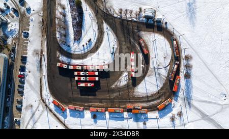 Drone photography of small terminal bus station with many parked buses and trolleybuses during winter sunny day Stock Photo