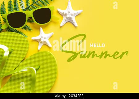 Hello Summer. Flat lay composition with sunglasses, starfish, seashells and beach flip flops with text Hello Summer over yellow background Stock Photo