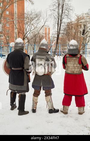 Three men dressed in defensive knight costumes stand in courtyard in winter. Stock Photo