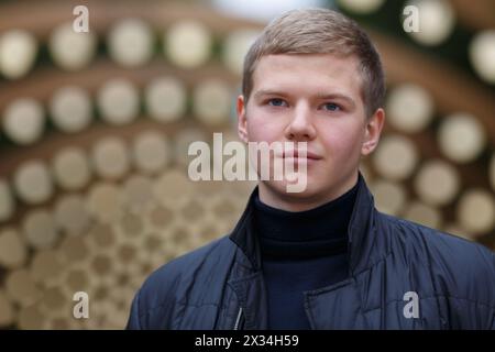 portrait of young man in black jacket on background of lights installation main park alley, close-up Stock Photo