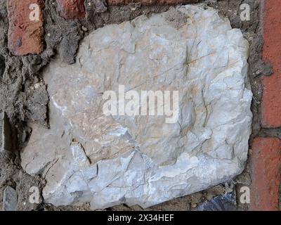 A close-up image of the weathered and textured surface of a natural stone material, which is composed of a mottled mix of gray and brown tones, inters Stock Photo