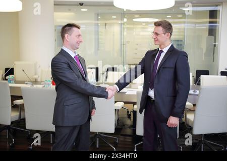 Two businessmen shaking hands in conference hall Stock Photo