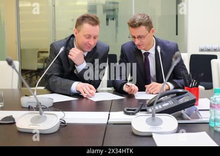 Two businessmen sitting at the table discussing documents Stock Photo