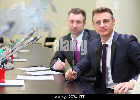 Portrait of two businessmen at negotiating table in conference hall Stock Photo