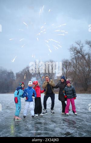 MOSCOW - NOV 30, 2014: Two adults and four children happy salute standing on ice skates at winter at outdoor skating rink Stock Photo