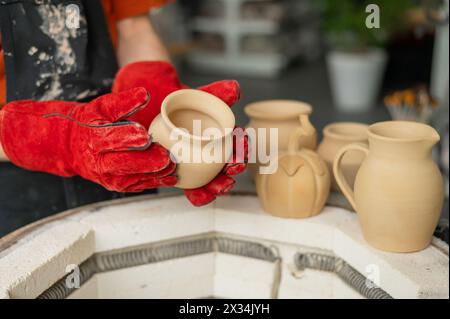 Close-up of a man's hands loading ceramics into a special kiln.  Stock Photo
