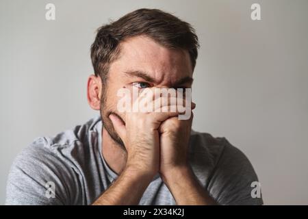 Stressed man covers his face with his hands closeup portrait. Mental illness and depression. Stock Photo