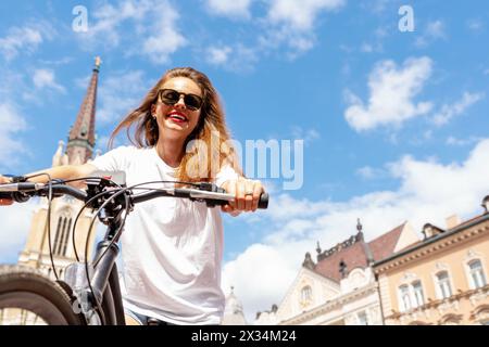 Carefree happy young woman traveling around the city on a bicycle. Summer active lifestyle. Stock Photo