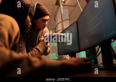 Hackers discussing computer system password cracking, coding malware, cybercrime. Criminals developing internet virus, scammers programming malicious software at night time Stock Photo