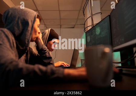 Diverse hackers breaking into professional database, stealing information and cracking passwords. Thieves using spyware and malicious theft to steal sensitive data. Cybercrime, hacking system. Stock Photo