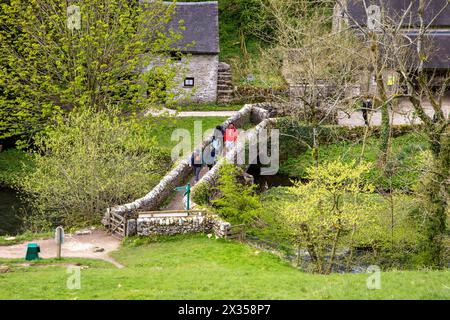 Walkers backpackers and ramblers crossing  VIATOR’S BRIDGE over the river Dove at Milldale in the English Peak District made famous by izaak Walton Stock Photo