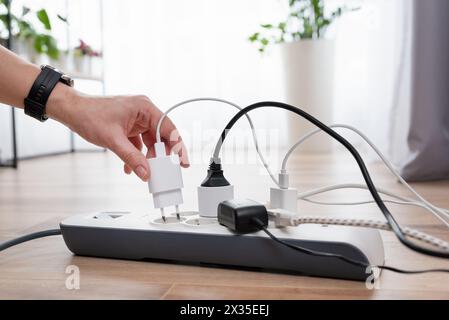 Man plugging the power plug. Electrical plug in outlet socket at home. Stock Photo