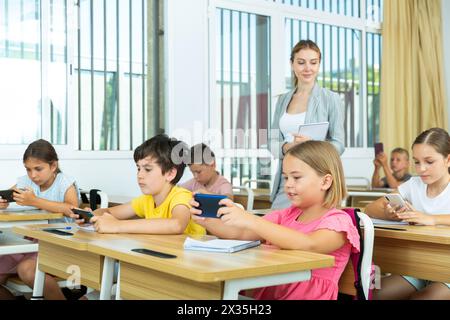 Pupils using mobile phones during lesson in school Stock Photo